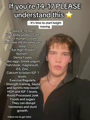 A young man with light skin and short, tousled brown hair is the focal point. He appears to be in his late teens or early twenties. He wears a dark, unzipped hoodie which is pulled up slightly, framing his face against a dark background. The image features text over it.