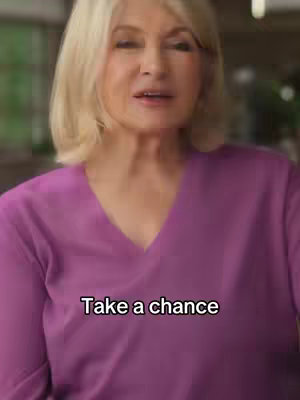 A woman in a purple v-neck top is centered in the frame, her blonde hair neatly styled. Text overlayed on the image reads, 'Take a chance,' in a clean sans-serif font.