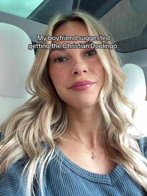 A woman in a car, looking at the camera. Text overlay says 'My boyfriend suggested getting the Christian Duolingo'.