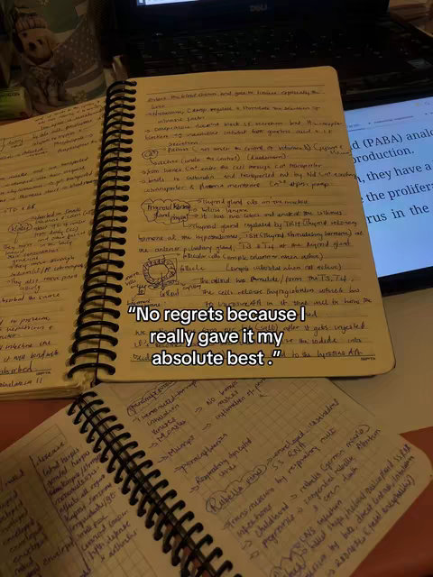 The image shows an open notebook with handwritten notes, a laptop on the right, and a second notebook in the foreground. The main notebook has text outlining medical information, and the foreground notebook has other notes. On the top notebook, under the spiral binding, there is a quote  "No regrets because I really gave it my absolute best."