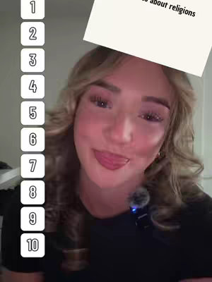 A person with fair skin and blonde wavy hair is in the foreground, with the upper body and face fully visible. The person is smiling with their tongue slightly out, and wearing a black top. To the left of the frame is a vertical list of numbers from one to ten. The background has a soft, blurred appearance.