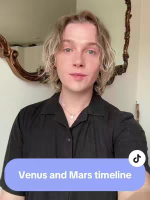 A young man with fair skin and light blond hair stands in front of a mirror. He wears a black button-down shirt and a delicate necklace. In the background, a decorative, ornate mirror is visible. A text overlay at the bottom of the image reads "Venus and Mars timeline" within a rounded rectangle, and the TikTok logo is displayed on the top right.