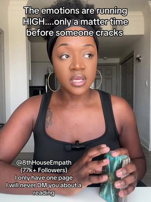 A woman with dark skin and curly black hair is the central focus of this image. She's positioned in the middle and looks slightly upwards, engaging directly with the viewer as she seemingly speaks. She has on large gold hoop earrings her gaze is intense. Text at the top reads: "The emotions are running HIGH....only a matter time before someone cracks". The background features elements of an indoor setting, with what appears to be door frames visible. The overall color scheme includes neutral tones, with the woman's skin providing a focal point against the dark surroundings.