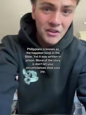 A young man in a black hoodie is centered in the frame. The background is blurry with neutral tones. Overlay text provides information on the Bible and the importance of joy despite difficult circumstances.