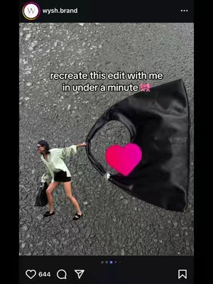 A woman in an oversized light green shirt and black shorts holds a large black tote bag, with a hot pink heart overlay, against a background of asphalt.
