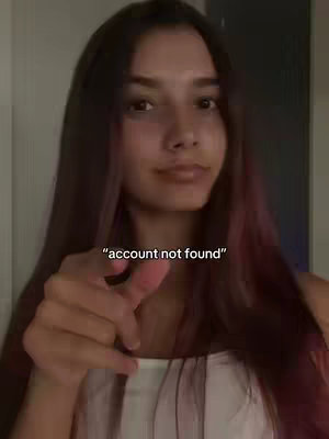 A young woman with long, dark hair is centered in the frame, gazing towards the camera. She's pointing a finger directly at the viewer. The background is a plain, neutral wall, and the text "account not found" is superimposed above and to the left of her finger, in a simple font.
