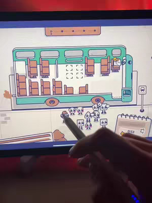The cover image showcases a casual, cartoon-style illustration of a bus scene within a gaming interface. A teal-colored bus is the focal point, with multiple seats visible inside. Small, rounded characters are positioned outside, appearing to interact with the game. Elements of a notebook and a stylus are also present within the scene, indicating a mobile or tablet gaming experience.