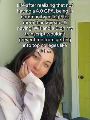 A selfie-style shot with the creator positioned in the bottom half, looking towards the camera. The background includes a partially visible green door on the right and a blurred view of what appears to be a window. The creator, a young woman with dark hair, is holding her hand up and appears to be thinking or pondering. The text overlay is white and stacked vertically, providing the context for the video's message about college experiences.