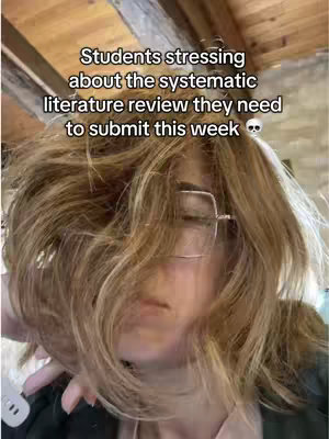 The cover image features a close-up of a person, their face partially obscured by their loosely styled, wavy blonde hair. They wear square-framed glasses. Text in the upper portion of the image reads about students stressing over literature reviews. The lighting appears to be natural, and the overall composition is focused and somewhat intimate.