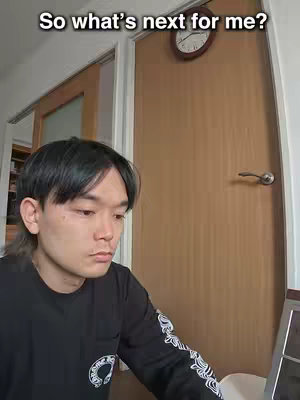 A man sits with a contemplative expression looking at a laptop, in a room with a wooden door and a clock on it. The words "So what's next for me?" appear at the top of the image, adding to the image's reflective and introspective tone.