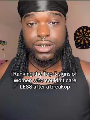A man with dark skin, black braids and a black durag is centered in a selfie-style shot. Text overlays the image, and a dartboard is visible in the background. The man has a nose ring, and a slight smile.