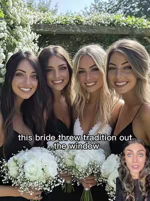 Four young women, posing closely together, with the one in the white dress in the center. They all have long hair and are smiling at the camera, each holding a bouquet of white flowers. The background includes a wall of green foliage and a glimpse of the sky. In the lower right corner, another woman's face is visible.
