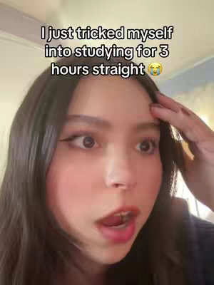 A selfie-style image featuring a young woman with dark hair, wide eyes, and an open mouth, as if in surprise. Text overlayed at the top reads, 'I just tricked myself into studying for 3 hours straight' with a crying emoji.