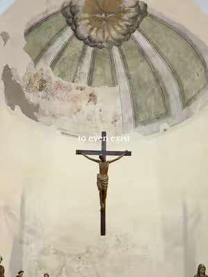 The image shows a religious scene inside a church. At the center is a wooden crucifix with a depiction of Jesus. The figure is sculpted with detailed features. Above the crucifix is a dome ceiling that looks weathered, with faded paint. The words ' to even exist' are in a simple font at the center. The lighting appears natural.