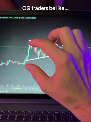 A person's hand is pointing at a stock chart on a laptop screen. The hand is lit with pink and purple light.