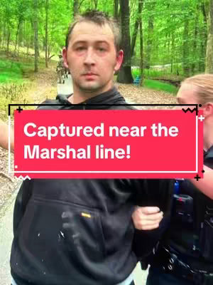 A man is being escorted by a law enforcement officer on a tree-lined path. A red text box with white text overlays the image.