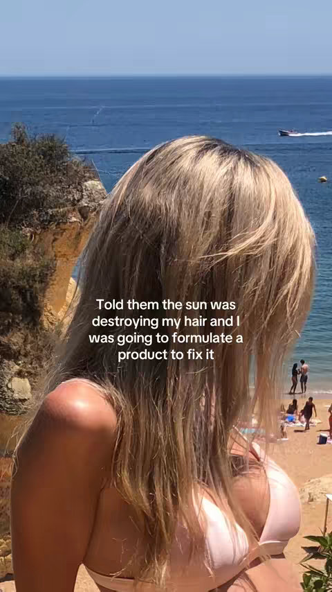 The cover image shows a woman with long blonde hair standing outdoors, with the ocean and a beach visible in the background. She is wearing a light-colored bikini top. Text overlayed on the image reads, "Told them the sun was destroying my hair and I was going to formulate a product to fix it."