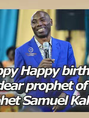 A man in a blue suit smiles while holding a microphone, with overlaid text and a blurred background.