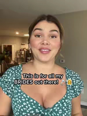 A woman with fair skin and brown hair is centered in the frame, facing the camera. She is wearing a green floral top. Overlay text states, 'This is for all my BRIDES out there!'