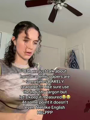 A young woman with curly hair is looking down and to the left with a serious expression. She's in a room with a ceiling fan and a laptop on a table. Text overlay is present on the image.