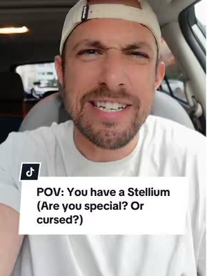 The cover image is a selfie featuring a man in a car. The man, who appears to be in his late 20s or early 30s, is wearing a white t-shirt and a backwards baseball cap. His expression is a mix of seriousness and slight amusement. Overlayed on the image is a white rectangle containing the text: 'POV: You have a Stellium (Are you special? Or cursed?)'. In the corner, the TikTok logo is visible. The background shows hints of the car's interior and a glimpse of the outside environment.