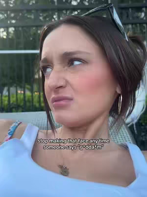 A woman with dark hair in a messy bun, and sunglasses on the top of her head, giving a disgusted facial expression. She is wearing a white top, and a gold earring. Text overlayed at the bottom of the image.