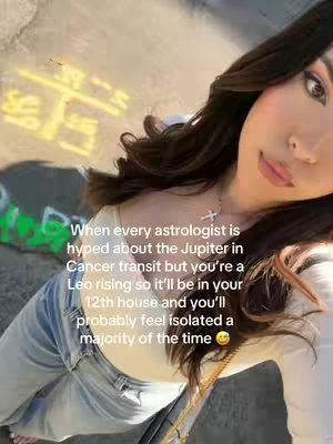 A selfie-style shot with a woman positioned at an angle, set outdoors with sunlight and a blurred background. She appears to be in comfortable attire, and text overlays her, discussing astrological transits and Leo risings.
