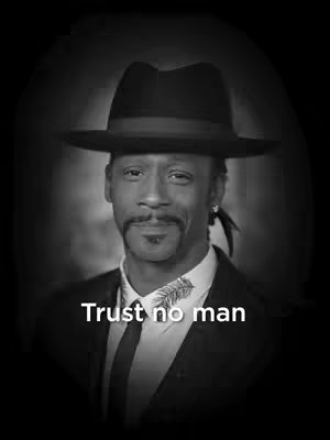 Black and white headshot of a man wearing a fedora hat and a dark suit. The man has a mustache and goatee. White text "Trust no man" is placed at the bottom of image.