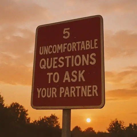 The image features a road sign in the foreground against a sunset backdrop. The sign, with a red background and white text, reads "5 UNCOMFORTABLE QUESTIONS TO ASK YOUR PARTNER". Behind the sign, a hazy orange sky is visible, with the sun appearing as a bright spot near the horizon. The overall composition is simple, with the sign clearly in focus and the sunset providing warm color and atmospheric depth.