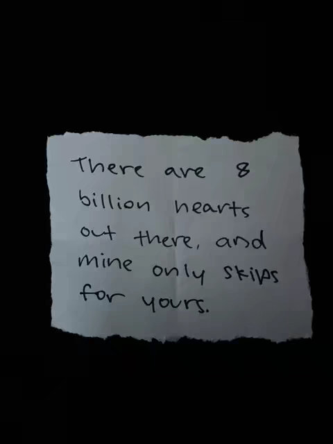 A piece of torn paper with a handwritten quote on a black background. The quote reads, 'There are 8 billion hearts out there, and mine only skips for yours.'