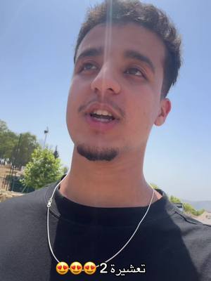 A man with short, dark hair looks up and slightly to the right, speaking. He wears a black t-shirt and a silver chain. At the bottom of the frame, text with emojis appears over the image.