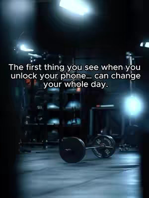 Dark and moody gym scene with a barbell centered in the foreground. The background shows exercise equipment, with text overlaid to give motivational message.