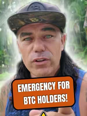 A man with long dark hair and a camo baseball cap looks at the camera. An orange rectangle with bold white text that reads "EMERGENCY FOR BTC HOLDERS!" appears in front of him.