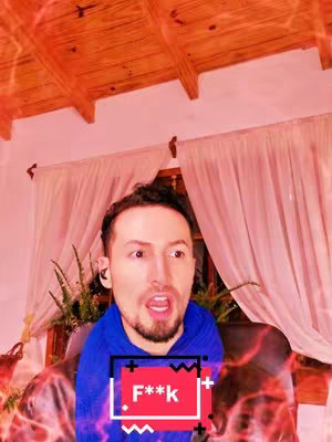 The cover image is a selfie-style shot of a man with short brown hair and a trimmed beard. He looks surprised with his mouth open. He is wearing a blue hoodie-style sweatshirt. The background is a warm-toned room with wooden beams and what appears to be pink curtains. A graphic overlay with the text 'F***k' is placed over the man's chest. There are red and orange visual effects emanating from the lower left and upper right of the frame.