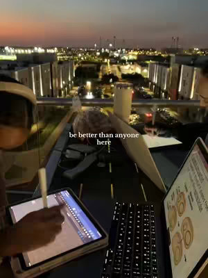 The cover image is of a rooftop scene at dusk. The foreground shows a person seated with a laptop and a tablet, with a pen in hand. The laptop screen shows a diagram. In the background, the city lights up the night sky and buildings.
