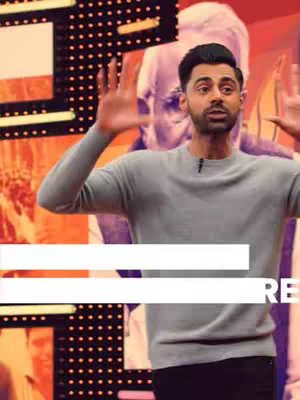The cover image features a man with dark hair and a focused expression, gesturing with open hands in a dynamic pose. He's wearing a gray sweater against a backdrop that includes a blurred image of an older man. The background incorporates orange and black color blocks. A horizontal white bar overlay contains text.