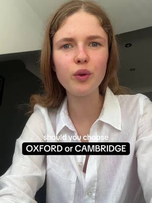 A medium shot captures a young woman with light skin and long, wavy blonde hair. She is positioned centrally, looking directly at the viewer with a neutral expression. Her upper body is visible, wearing a white collared shirt. Overlaying the image at the bottom is a black rectangle with white text, posing the question: 'OXFORD or CAMBRIDGE.' The background suggests a well-lit interior with neutral colors and a window or light source above and to the left.