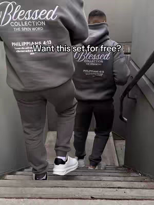 Two people wearing matching gray hoodies and sweatpants are walking down a set of stairs. The hoodies have a logo on the back and text on the back and front. The image is well-lit, and the composition emphasizes the clothing and the act of walking.