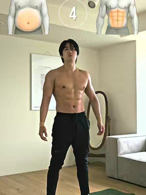 A man with a muscular, shirtless torso stands facing the camera. Behind him is a light-colored wall with a framed picture. A mirror and a couch are visible to the right. The image features comparisons of a fat belly to six-pack abs for added emphasis toward the objective.