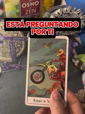 The cover image presents a tarot card held in a hand, with a black rectangular overlay at the top. The tarot card is the Knight of Swords, showing a person on a motorcycle. The background is cluttered, with various objects and other decorative elements around the card. The top overlay has text in white and red.
