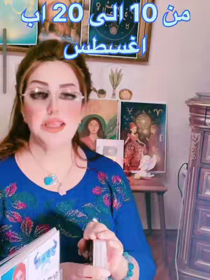 A woman with glasses is holding tarot cards and smiling. The background includes a decorative wooden cabinet, artwork and candles. Text is superimposed above the woman and visible in the frame.