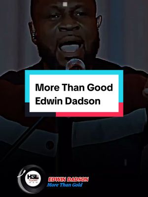 The image showcases a man singing into a microphone with a text overlay. The man has dark skin, a dark shirt, and a light-colored cross on his forehead. The text overlay, with a white background and blue and red borders, displays the song title and artist's name. A logo with text is at the bottom, representing the artist's name and song title. The background appears to be a dark stage setting.
