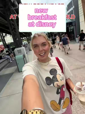 A selfie-style image with the creator smiling at the camera. The background features a blurred street scene with other people walking by. Text overlays appear in a rectangular box at the top, and the creator is wearing a Mickey Mouse t-shirt and holding a drink.