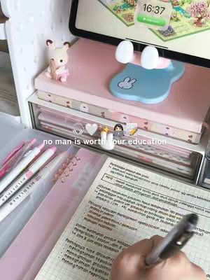 A well-lit workspace with pink and white aesthetic. A hand is writing on a sheet of paper, several pink highlighters are in view. An iPad displays with the time 16:37, and a bunny-shaped phone stand along with a bunny figurine. The text overlay reads 'no man is worth your education.'