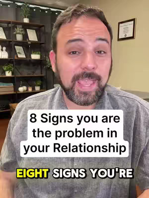 The image is a selfie-style video cover featuring a man in his late 30s or early 40s with a well-groomed beard. He looks directly at the camera with his mouth slightly open. He is wearing a gray collared shirt. A white text box states '8 Signs you are the problem in your Relationship' with the phrase 'EIGHT SIGNS YOU'RE' in yellow.