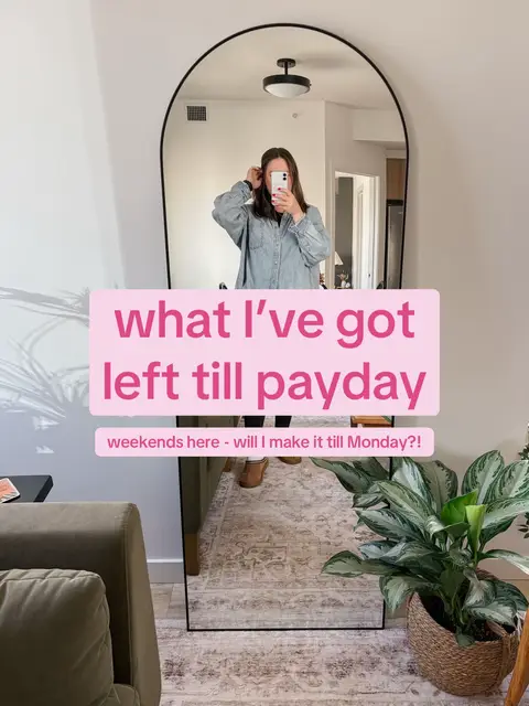 A selfie taken in a well-lit room shows a woman reflected in a large, arched mirror. She is holding a phone in front of her face, obscuring her features. The mirror reflects the room's contents, including a green armchair, a patterned rug, and a potted plant. Overlaid on the image is a pink rectangle with the text "what I've got left till payday" and a smaller text beneath it.