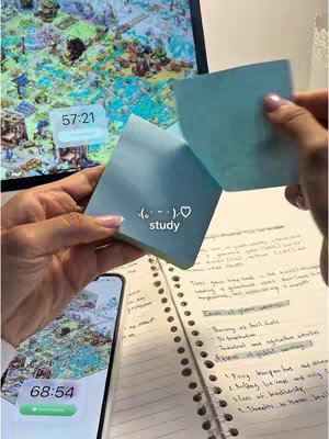 The cover image shows a person's hands holding a stack of light blue sticky notes.  The notes have the word "study" with a heart emoji. The person is holding it in front of notebook paper with handwritten text, with the phone and computer visible in the background.  On the phone screen is an app with a timer and green start button.  The monitor shows a game and a visible timer on the top left.