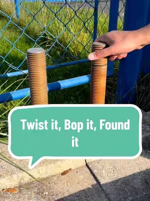 A hand is reaching to twist a cylindrical bolt next to two others. The bolt is next to a blue fence and a chain link fence in the background. A speech bubble with the words "Twist it, Bop it, Found it" overlaid on the bottom.