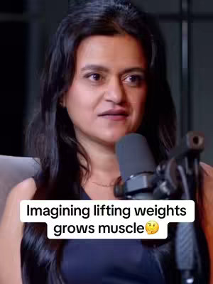 A woman with dark hair is positioned slightly off-center, looking towards the left side of the frame. A microphone is placed in front of her, suggesting a podcast or interview setting. The background appears blurred, contributing to the focus on the woman. Overlayed text is present, featuring a statement about mental muscle growth. The color palette is muted with simple lighting.
