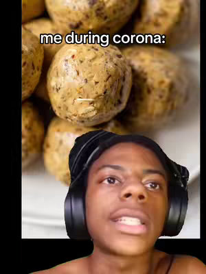 The image shows a close up of what appears to be round, baked goods, with a creator's face in the lower part of the frame. The food items are tan and have flecks of what may be seeds or spices on their surface. The creator is in the lower section, on one side, with headphones around the neck. The background seems to be the interior of a home.